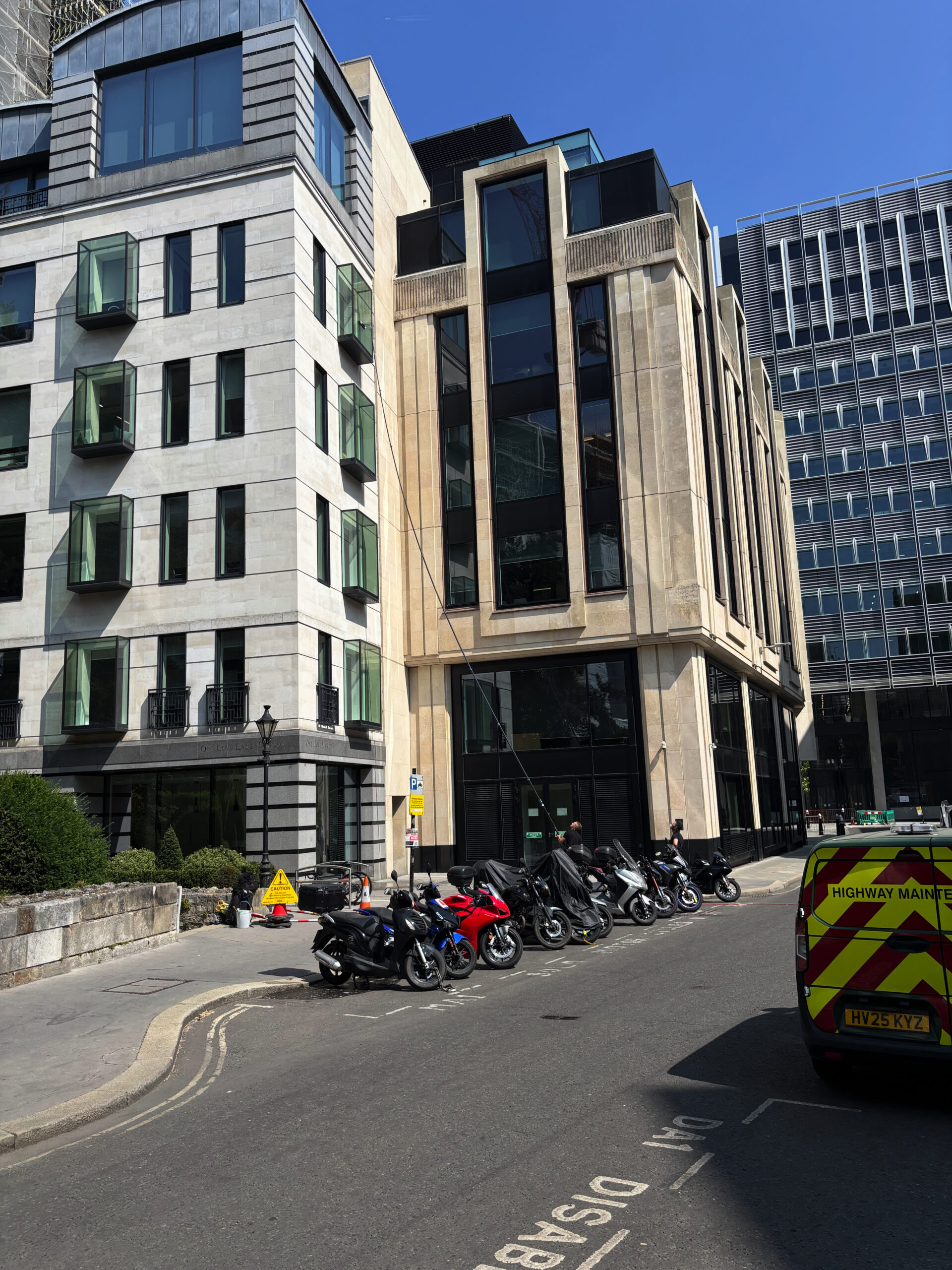 A man cleaning a fourth-floor office window with an incredibly long brush. I am sure that this takes some significant skill not to lose his balance and clobber a passer-by in the street.